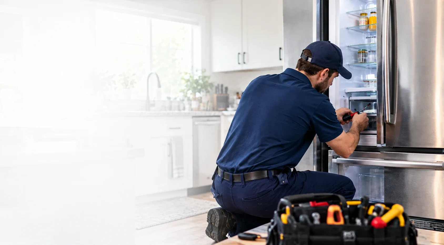 Fridge Masters technician repairing a stainless steel refrigerator in a Fort Myers kitchen