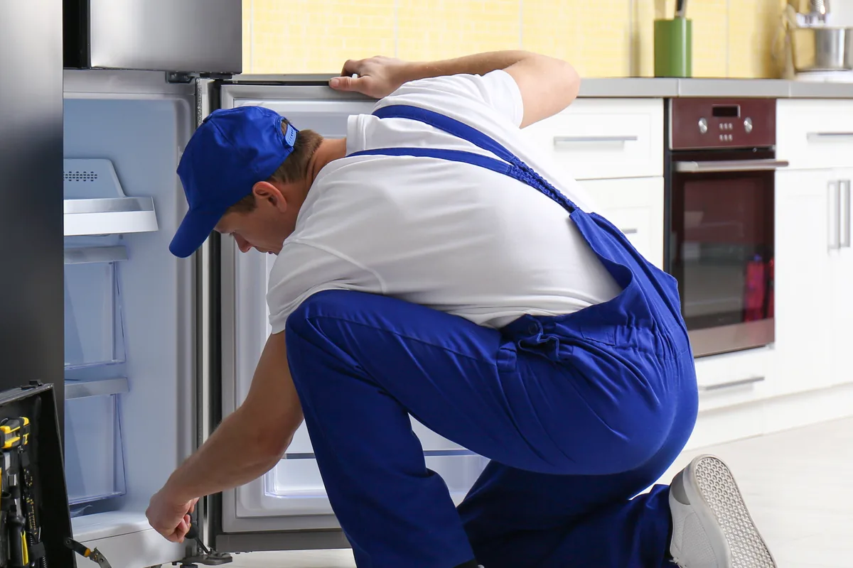 Technician working on a refrigerator in a kitchen